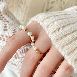 Detailed view of champagne gold pearl wrap ring worn on finger with soft knit background