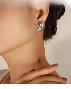 Close-up of polished silver water-drop earrings with organic irregular curved metal design