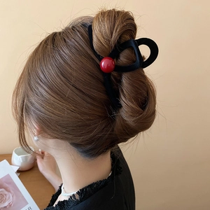 Close-up of black velvet hair claw clip with a single red bead accent on model