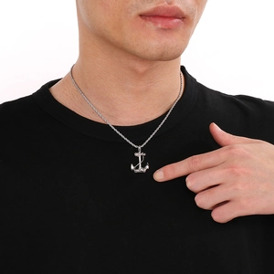 Close-up of a men's silver anchor pendant with a rope chain worn on a black t-shirt