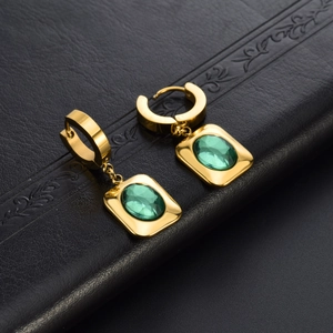 Luxurious gold titanium earrings featuring emerald green oval zirconia on black leather
