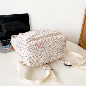 Detailed view of floral canvas backpack with adjustable straps on a white table