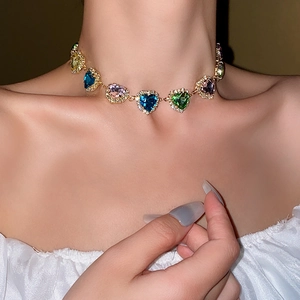 Close-up of golden necklace featuring colorful heart-shaped gemstones worn by a model