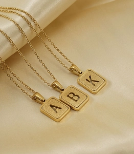 Detalle de colgantes cuadrados de acero inoxidable chapado en oro de 18K con letras A, B y K