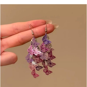 Détail de boucles d'oreilles papillon ajourées avec pampilles dégradées violettes et fuchsia