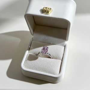 Oval pink zircon ring in silver four-prong setting inside a white luxury crown gift box