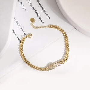 Detail of gold paperclip chain bracelet featuring pavé zircon eye and pin charm