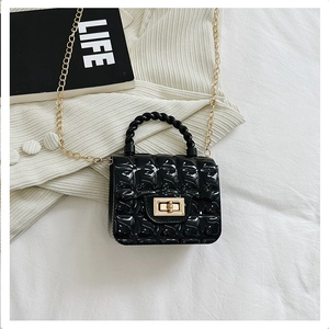 Detail of black quilted jelly bag with golden metallic twist lock and chain strap