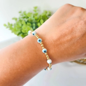 Bohemian 18k gold plated evil eye beaded bracelet worn on wrist with natural background