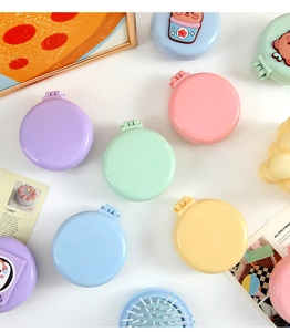 Macro detail of portable macaroon folding hairbrushes with mirror and cartoon decor