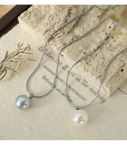 Detail of silver snake chain necklaces with large white and grey pearl pendants