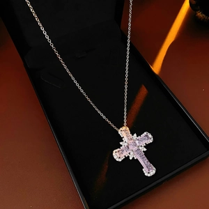 Detail of cross pendant with pink emerald-cut zircon in a black jewelry gift box