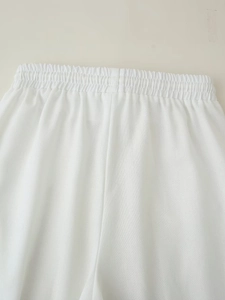 Detail of white cotton linen trousers featuring elastic waistband and breathable texture