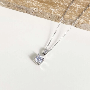 Detail of four-prong solitaire necklace with round zircon and sparkling stone accents