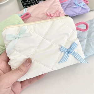 Close-up of a quilted pearlescent pouch with a bow, featuring multiple pastel color options