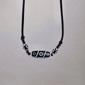 Ethnic nine-eye dZi bead necklace with black adjustable cord and hand-woven details