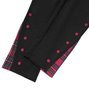 Détail du pantalon noir avec boutons rouges et empiècements en tissu écossais tartan