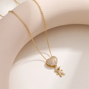 Dettaglio del ciondolo a cuore dorato con zirconi e charm bambino su catena sottile