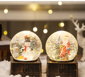 Close-up of vintage bronze Christmas snow globe with snowman and warm bokeh lights