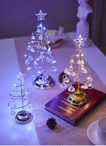 Macro shot of spiral iron Christmas trees with glowing LED lights and crystal pendants