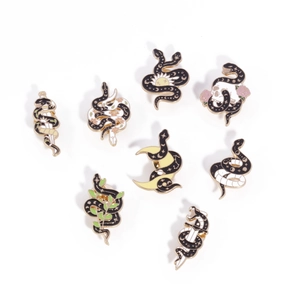 Set of 8 gothic snake enamel pins featuring daggers, skulls, and moons on white background
