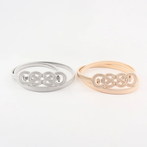 Detail of gold and silver metal elastic belts with decorative braided twist buckles