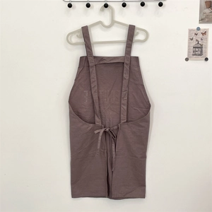 Detail of cross-back tie design on pink linen cotton apron with printed letters