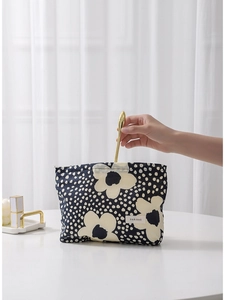 Floral makeup bag with navy polka dots pattern shown with a makeup brush being inserted