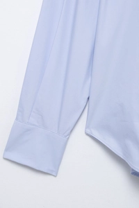 Detailed close-up of light blue striped shirt sleeve cuffs and hem stitching texture