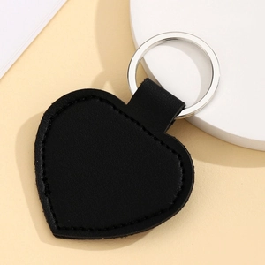 Close-up of a heart-shaped black PU leather keychain with a polished metal ring detail