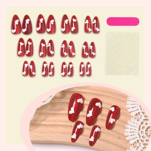 Red cat eye almond press-on nails with white heart patterns and application tool kit