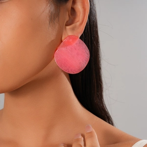 Close-up of a large pink resin hoop earring with horizontal texture on female model