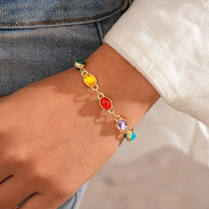 Detail of gold chain bracelet with five colorful oval resin stones on a model's wrist