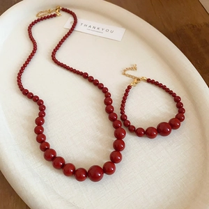 Détail de l'ensemble collier et bracelet de perles rouges avec fermoir doré sur plateau