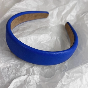 Detail of Klein blue faux leather headband featuring lychee texture and soft brown lining