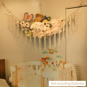 Handmade macrame toy hammock with fringes and star lights in a nursery setting