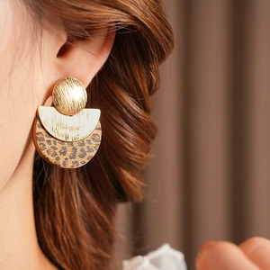Close-up of elegant gold metal leopard print round earrings on a model’s ear
