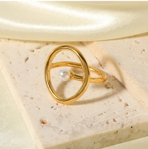 Detailed close-up of a vintage gold-plated ring with a white pearl on a marble surface