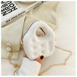 Detailed shot of white glossy PVC mini jelly bag with gold chain strap held by hand