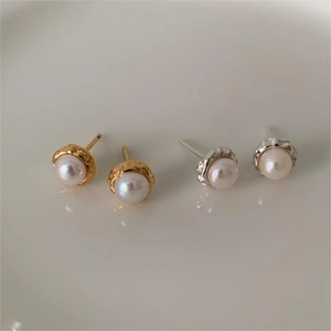 Detail of minimalist irregular pearl studs with gold and silver lava texture edges