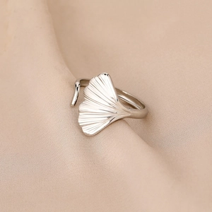 Close-up of silver ginkgo leaf ring with intricate vein textures on silk background