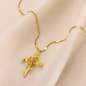 Macro view of gold-plated birth flower cross necklace on elegant silk background