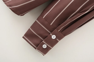 Detail shot of shirt cuff with coffee and white vertical stripes and two white buttons