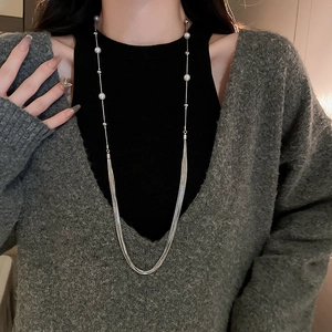 Detailed close-up of a layered pearl necklace showing elegant fringe and metallic chains
