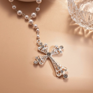 Detailed close-up of a silver hollow cross pendant with rhinestones and pearl chain