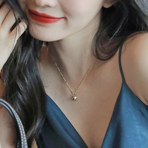 Detailed close-up of a golden heart pendant necklace on a blue satin background