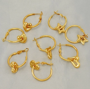 Macro view of gold-plated stainless steel star and heart earrings on satin fabric
