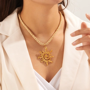 Collier avec pendentif soleil doré et chaîne de corde torsadée porté par un modèle