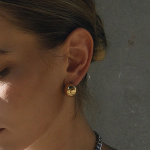 Polished gold hollow sphere stud earrings for women shown on model for a luxury look