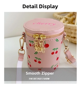 Detail of pink cylindrical crossbody bag with cherry prints and golden cherry zippers